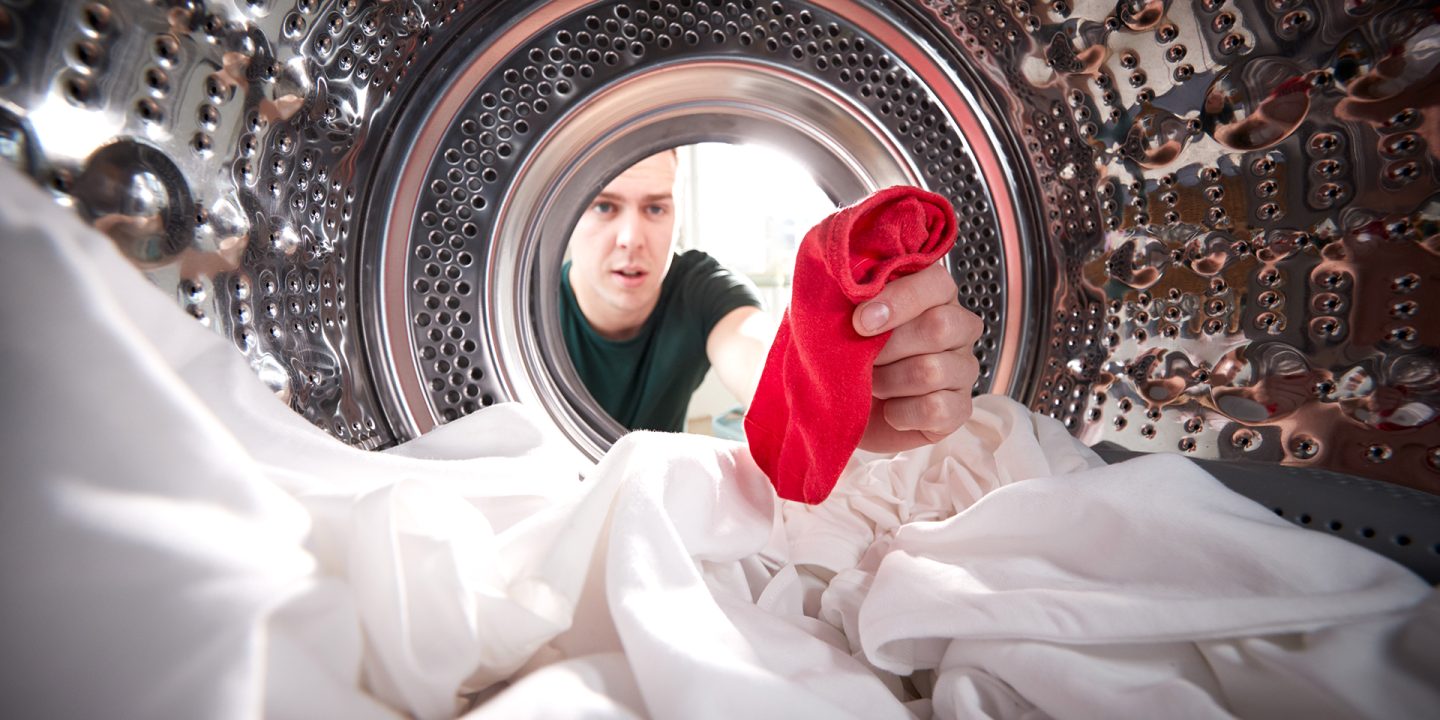 Man Taking Out Red Sock Mixed With White Laundry From Washing Machine